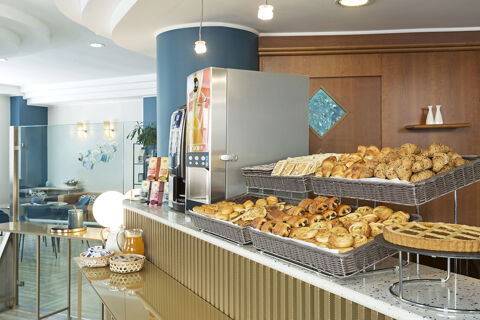 Breakfast buffet with various pastries, coffee machine, juice, and condiments on the counter at B&B Hotel Pescara