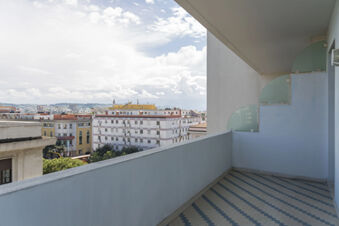 Empty balcony at B&B Hotel Pescara with blue and white tiled floor and city buildings under a cloudy sky visible outside