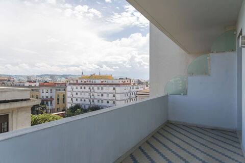 Empty balcony at B&B Hotel Pescara with blue and white tiled floor and city buildings under a cloudy sky visible outside