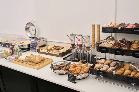 Breakfast buffet with croissants, pastries, bread, spreads, and syrup dispensers at B&B Hotel Napoli dining area