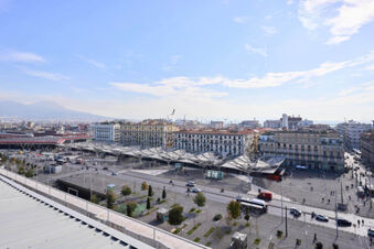 View of Piazza Garibaldi with buses, cars, people, and buildings under a partly cloudy sky at B&B Hotel Napoli