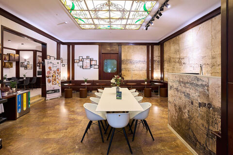 Dining area with white chairs around a table, brown stools, framed pictures, and a decorative ceiling at B&B Hotel Napoli