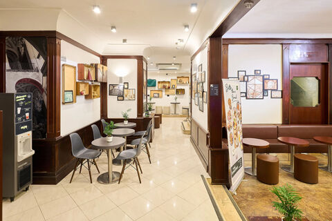 Interior of B&B Hotel Napoli with modern seating areas, small round tables, plants, and framed wall decorations