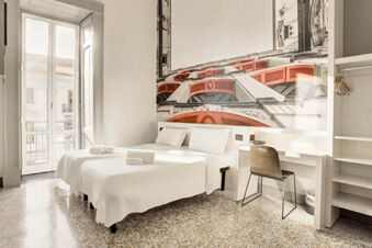 Two single beds with white linens and towels are arranged next to a window and a desk with a chair at B&B Hotel Napoli