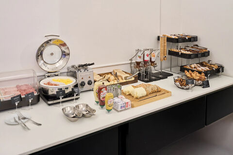 Breakfast buffet with sliced bread, cold cuts, scrambled eggs, condiments, pastries, and jam dispensers at B&B Hotel Napoli