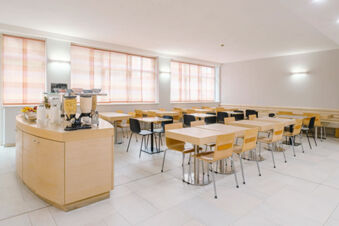 Light and spacious breakfast area with tables, chairs, and cereal dispensers at B&B Hotel Reggio Emilia Remilia