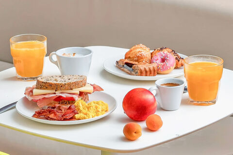Breakfast spread with sandwiches, scrambled eggs, bacon, pastries, fruit, orange juice, and coffee at B&B Hotel Reggio Emilia Remilia