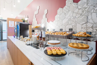 Breakfast buffet with pastries, cakes, croissants, jars, plates, and dispensers at B&B Hotel Trieste breakfast area
