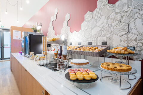 Breakfast buffet with pastries, cakes, croissants, jars, plates, and dispensers at B&B Hotel Trieste breakfast area