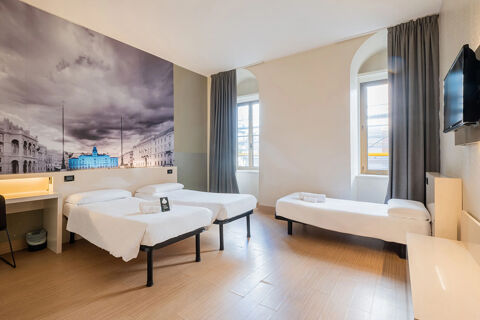 Hotel room at B&B Hotel Trieste featuring two single beds, a single bed, a wall-mounted TV, and a large cityscape mural