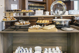 Breakfast buffet includes croissants, bread rolls, sliced bread, pastries, and a chafing dish at B&B Hotel Pomezia Cortese