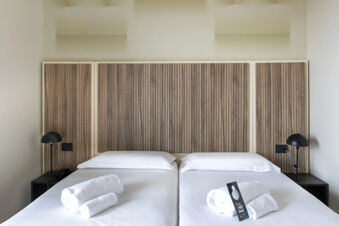 Two single beds with white linens and rolled towels with a "Do Not Disturb" sign in B&B Hotel Pomezia Cortese
