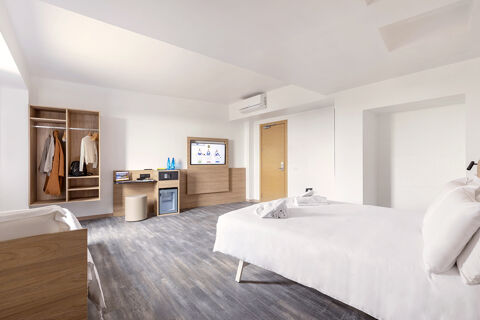 Bright hotel room at B&B Hotel Pomezia Roma with a large bed, wooden furniture, open closet, and TV on the wall