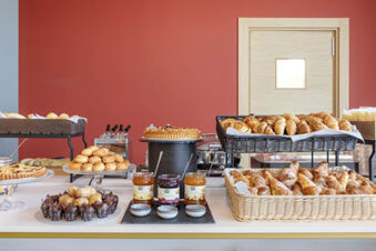 Breakfast buffet with assorted pastries, jams, and breads displayed on a counter at B&B Hotel Roma Fiumicino Aeroporto Fiera 2
