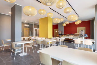 Dining area with white tables, wooden chairs, yellow and red walls, and hanging rattan light fixtures at B&B Hotel Roma Fiumicino Aeroporto Fiera 2