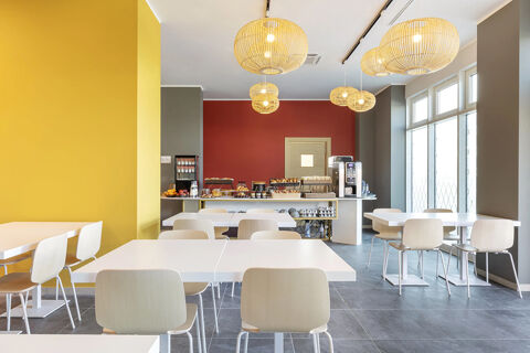Dining area with white tables and chairs, hanging lamps, and a buffet with snacks and drinks at B&B Hotel Roma Fiumicino Aeroporto Fiera 2