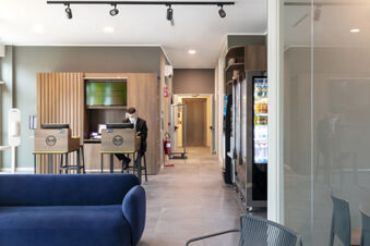 Man in a suit working at the reception desk in a modern hotel lobby at B&B Hotel Roma Fiumicino Aeroporto Fiera 2