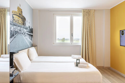 Hotel room with two single beds, white linens, yellow patterned curtains, and a large wall mural at B&B Hotel Roma Fiumicino Aeroporto Fiera 2