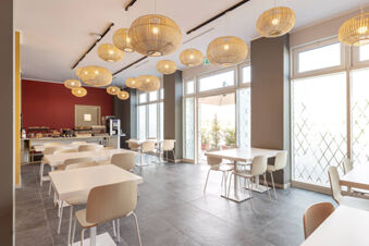 Bright dining area with white tables, wooden chairs, hanging wicker lamps, and a buffet counter at B&B Hotel Roma Fiumicino Aeroporto Fiera 2