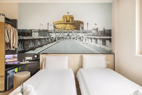Hotel room at B&B Hotel Roma Fiumicino Aeroporto Fiera 2 with two single beds, a large wall art, and a small work desk area