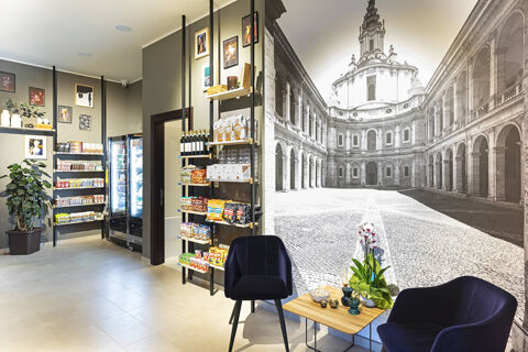 Seating area with two blue chairs and a table with decorative items next to a large black and white historic building mural at B&B Hotel Roma Fiumicino Aeroporto Fiera