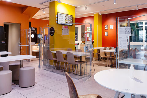 Interior view of B&B Hotel Roma Pietralata Tiburtina dining area with white tables, chairs, orange and yellow walls, and glass partitions