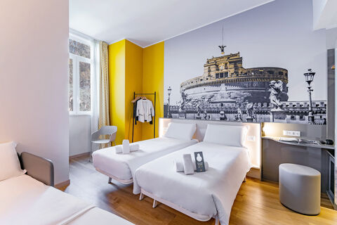 Bright hotel room at B&B Hotel Roma Pietralata Tiburtina with two single beds, yellow accent wall, and large window