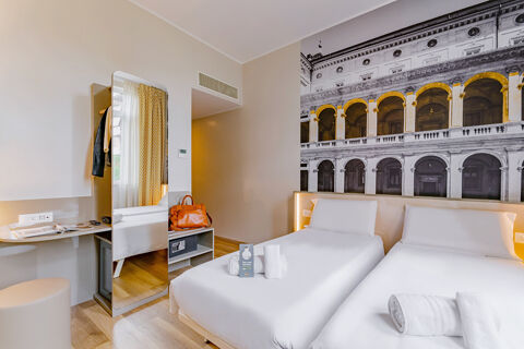 Hotel room at B&B Hotel Roma Pietralata Tiburtina with two single beds, a large wall mural, and a full-length mirror