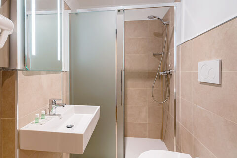 Bathroom sink with soap and shampoo bottles next to a shower cabin with glass doors at B&B Hotel Roma Pietralata Tiburtina
