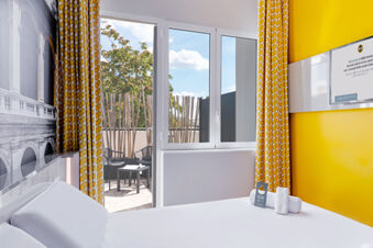 Hotel room at B&B Hotel Roma Pietralata Tiburtina with a white bed, yellow patterned curtains, and a door to an outdoor patio area
