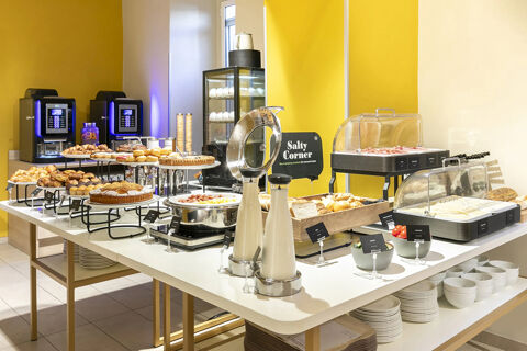 Breakfast buffet with pastries, bread, cold cuts, condiments, and two coffee machines at B&B Hotel Roma San Lorenzo Termini