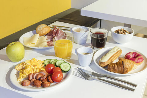 Breakfast spread on white tables with scrambled eggs, sausage, fruit, pastries, coffee, and juice at B&B Hotel Roma San Lorenzo Termini