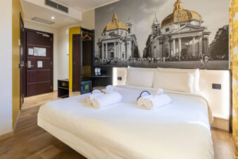 Hotel room at B&B Hotel Roma San Lorenzo Termini featuring a large bed with white linens and rolled towels on top