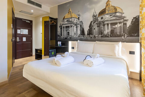 Hotel room at B&B Hotel Roma San Lorenzo Termini featuring a large bed with white linens and rolled towels on top