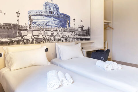 Two neatly made single beds with rolled white towels, a desk, chair, open closet, and black and white wall art at B&B Hotel Roma Trastevere