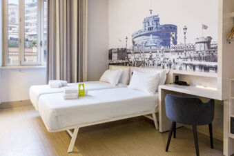 Two single beds with white linens and towels in a room at B&B Hotel Roma Trastevere with a large black and white wall mural and a desk with a black chair