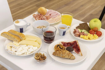 Breakfast spread with bread, cheese, cold cuts, cereals, scrambled eggs, fruit, coffee, juice, and pastries at B&B Hotel Roma Trastevere
