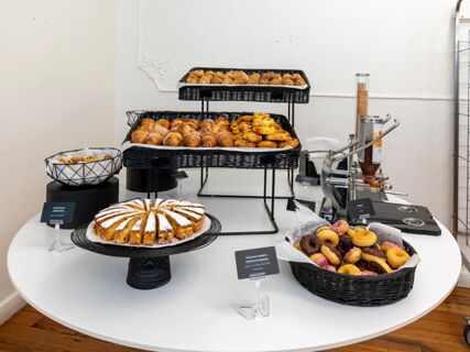 Assorted pastries including croissants, donuts, and cake slices arranged in baskets on a table at B&B Hotel Genova Principe