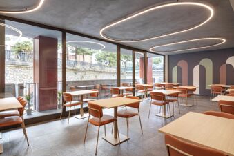 B&B Hotel Genova City Center modern dining area with circular ceiling lights, orange chairs, wooden tables, and large windows