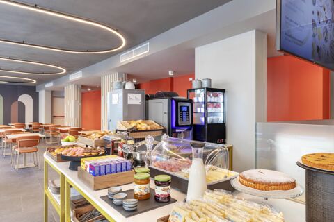 Snack and breakfast buffet with pastries, jam jars, sliced meats, cheese, and juice in B&B Hotel Genova City Center dining area