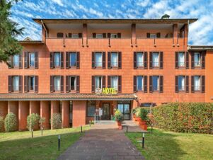 Three-story building facade with brown window shutters and covered balconies under a blue sky at B&B Hotel Bergamo City