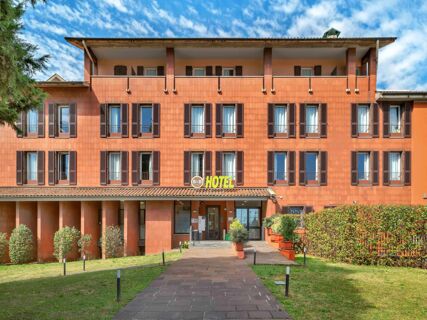 Three-story building facade with brown window shutters and covered balconies under a blue sky at B&B Hotel Bergamo City