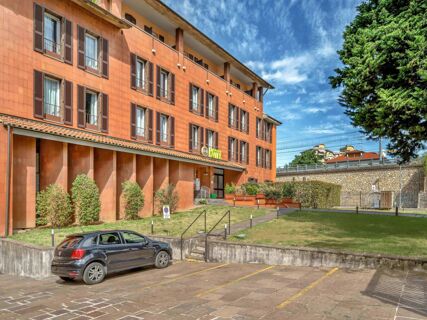 Exterior view of B&B Hotel Bergamo City showing a three-story terracotta building with multiple windows and a parked black car nearby