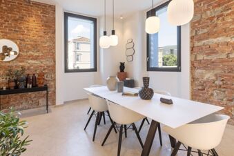Modern dining area with white table and chairs, decorative vases, pendant lights, exposed brick walls, and windows at B&B Hotel Brescia