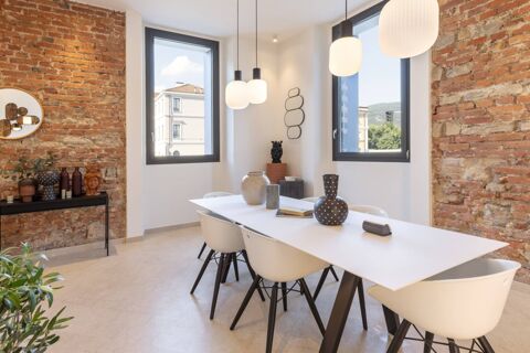 Modern dining area with white table and chairs, decorative vases, pendant lights, exposed brick walls, and windows at B&B Hotel Brescia