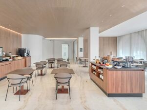 Dining area with wooden tables and chairs and a breakfast buffet island in B&B Hotel Habitat Giussano dining room