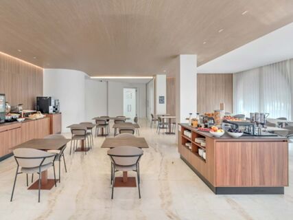 Dining area with wooden tables and chairs and a breakfast buffet island in B&B Hotel Habitat Giussano dining room