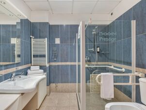 Bathroom with blue and beige tiles, white sink, towel rack, shower with glass door, and B&B Hotel Hotel Prestige Ornago sign