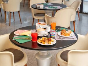 Breakfast spread with juice, coffee, yogurt, cold cuts, pastries, and cereal on a table at B&B Hotel Hotel Prestige Ornago