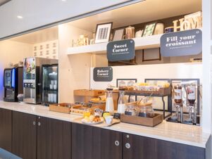 Self-service breakfast area with coffee machines, cereal jars, pastries, milk pitchers, and signs at B&B Hotel Mantova